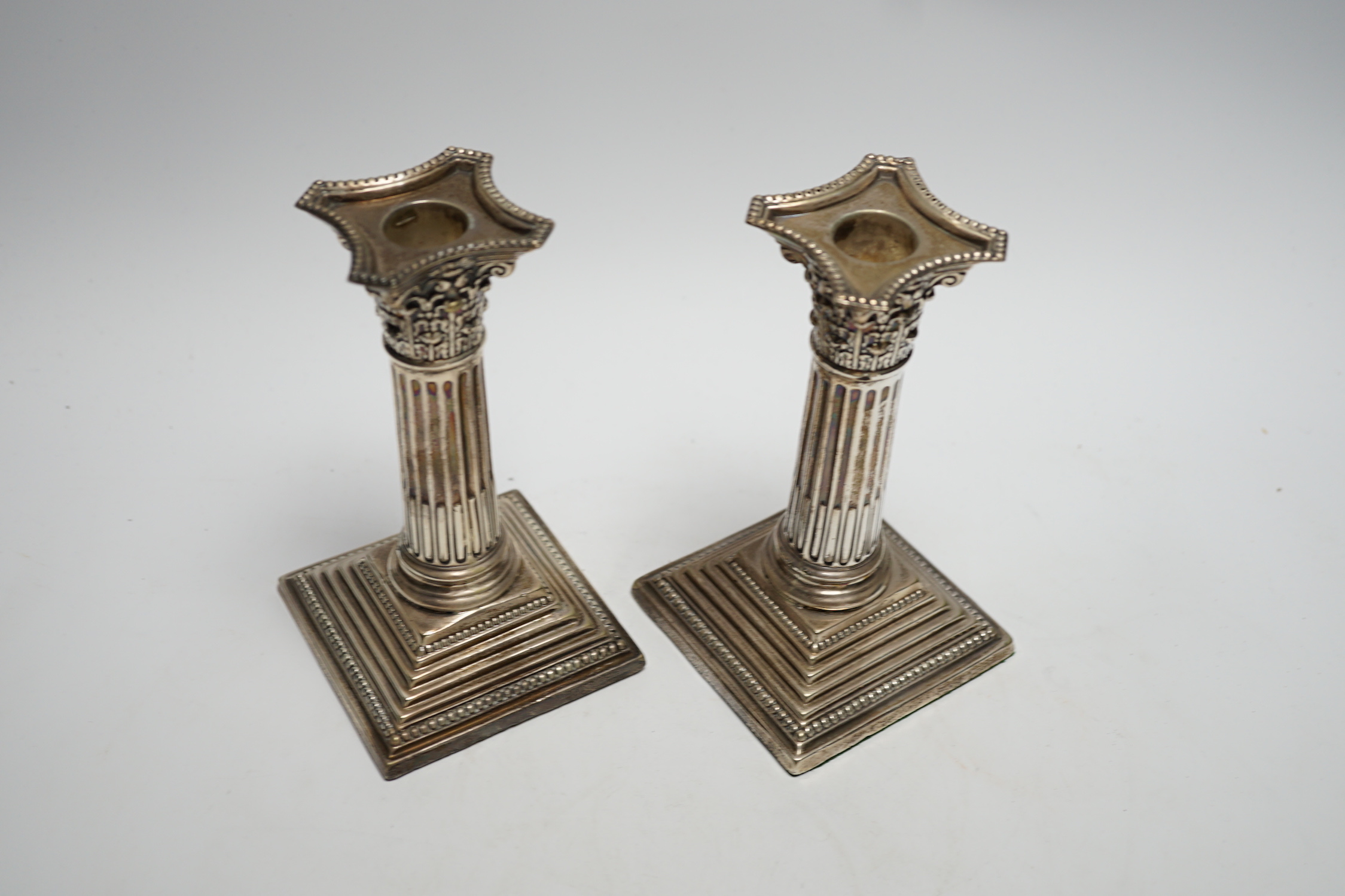 A pair of George V silver mounted Corinthian column dwarf candlesticks, London, 1911, 15.7cm, weighted.